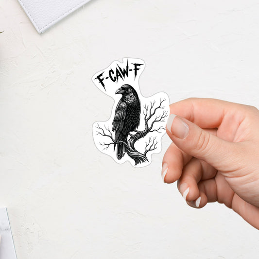 Hand holding a sticker with a black and white illustration of a crow on a branch and 'F-CAW-F' text.